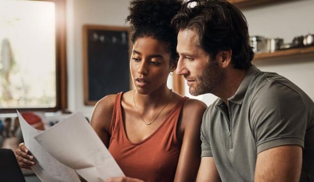 Couple looking at paper and computer