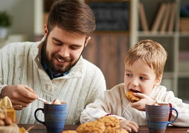 Father and son drinking hot chocolate at the kitchen table.